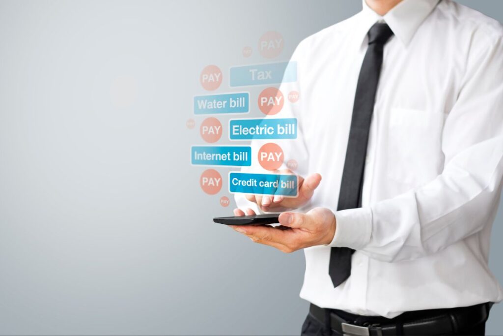 Homem de negócios usando um smartphone para pagar contas, com ícones flutuantes de contas de água, luz, internet e cartão de crédito. Uma representação visual do gerenciamento financeiro de forma ágil e eficiente oferecido pelos bancos digitais.
