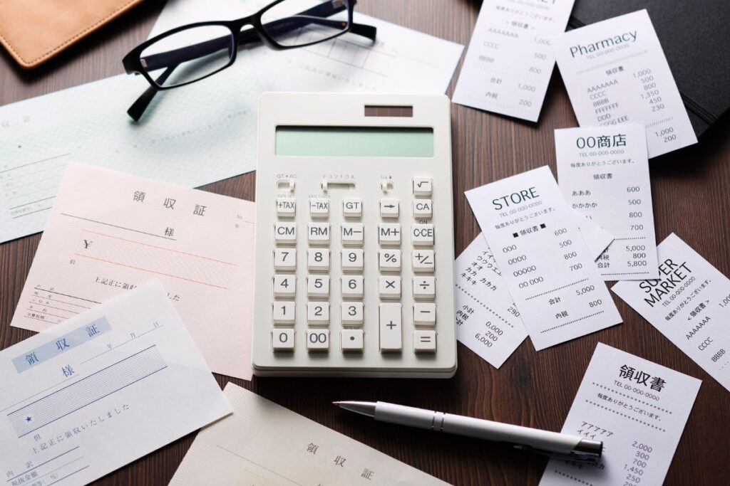 Calculadora cercada por recibos e notas fiscais usadas no controle de gastos pessoais.