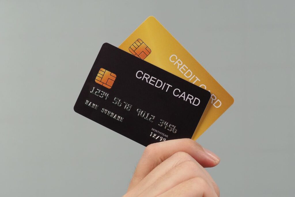 Pessoa segurando cartões de débito e crédito nas cores preta e dourada