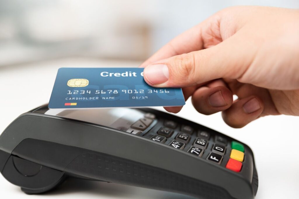 Cartão de crédito sendo inserido em máquina de pagamento, representando o uso de cartões de débito e crédito