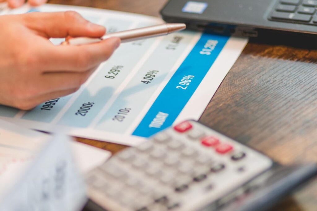 Mão apontando para uma taxa de 2.96% em um relatório, simbolizando a análise de juros abusivos.