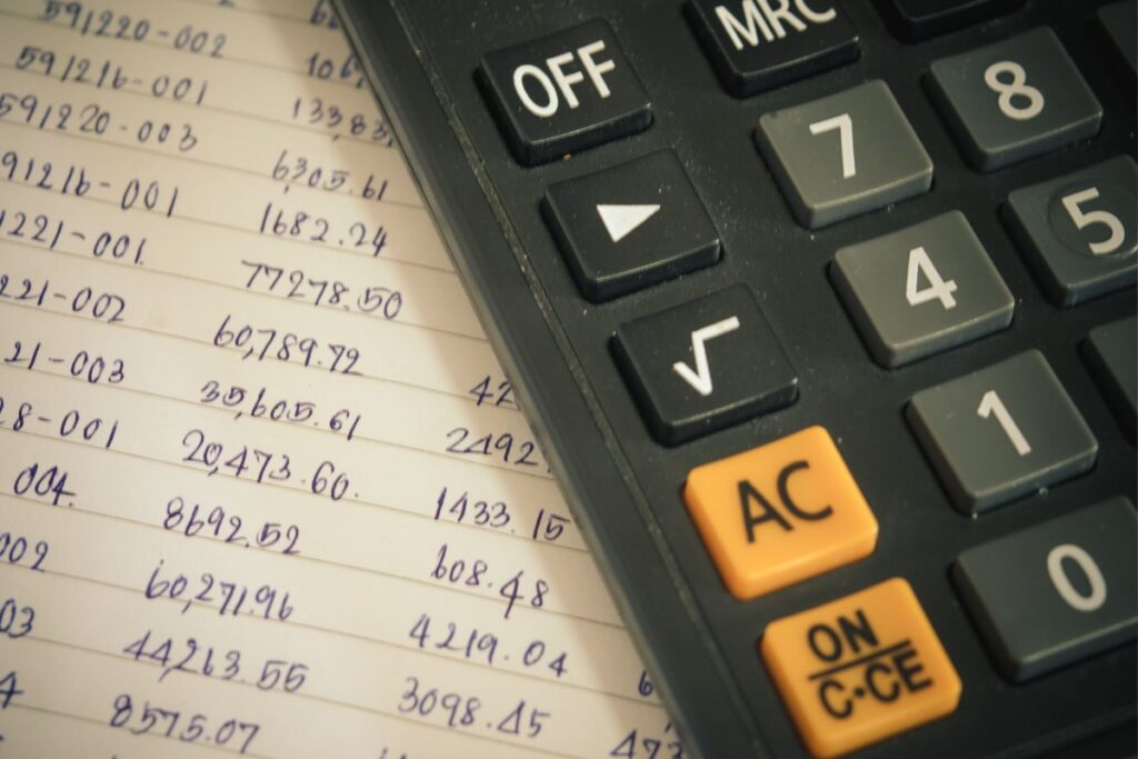 Calculadora sobre uma folha de anotações com números e cálculos, essencial para confrontar os juros excessivos.