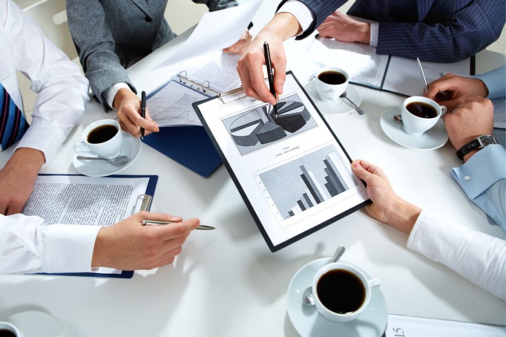 Equipe de negócios em reunião analisando relatórios e o plano financeiro.