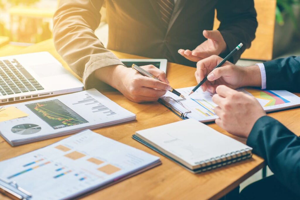 Dois empreendedores revisando um plano de negócios com gráficos e relatórios financeiros detalhados.
