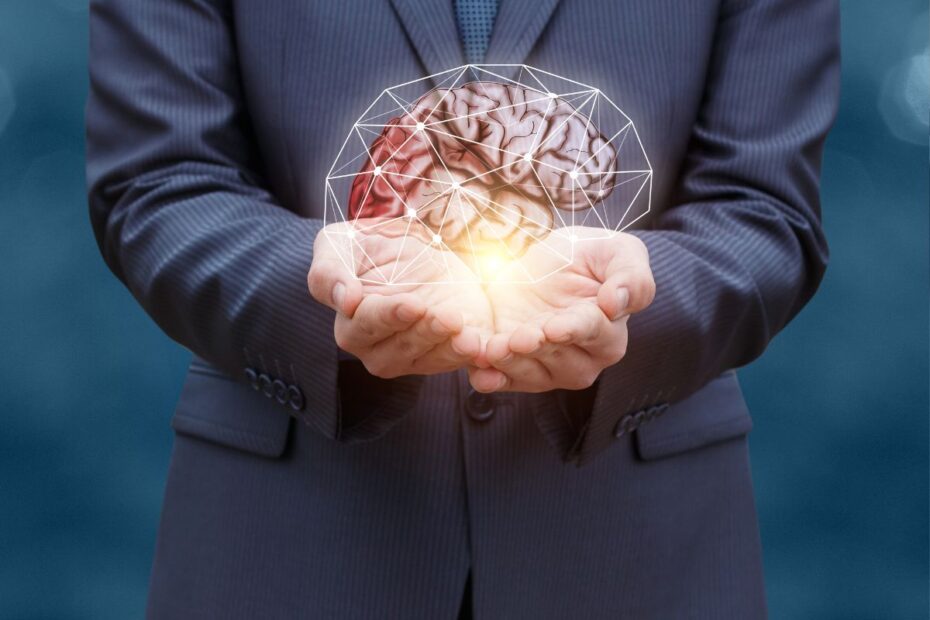 Homem de terno segurando cérebro holográfico iluminado representando mentalidade financeira e transformação mental