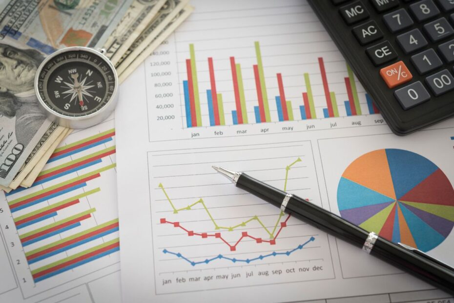 Uma bússola, dinheiro e gráficos de desempenho financeiro em uma mesa, representando a análise de dados no planejamento financeiro.