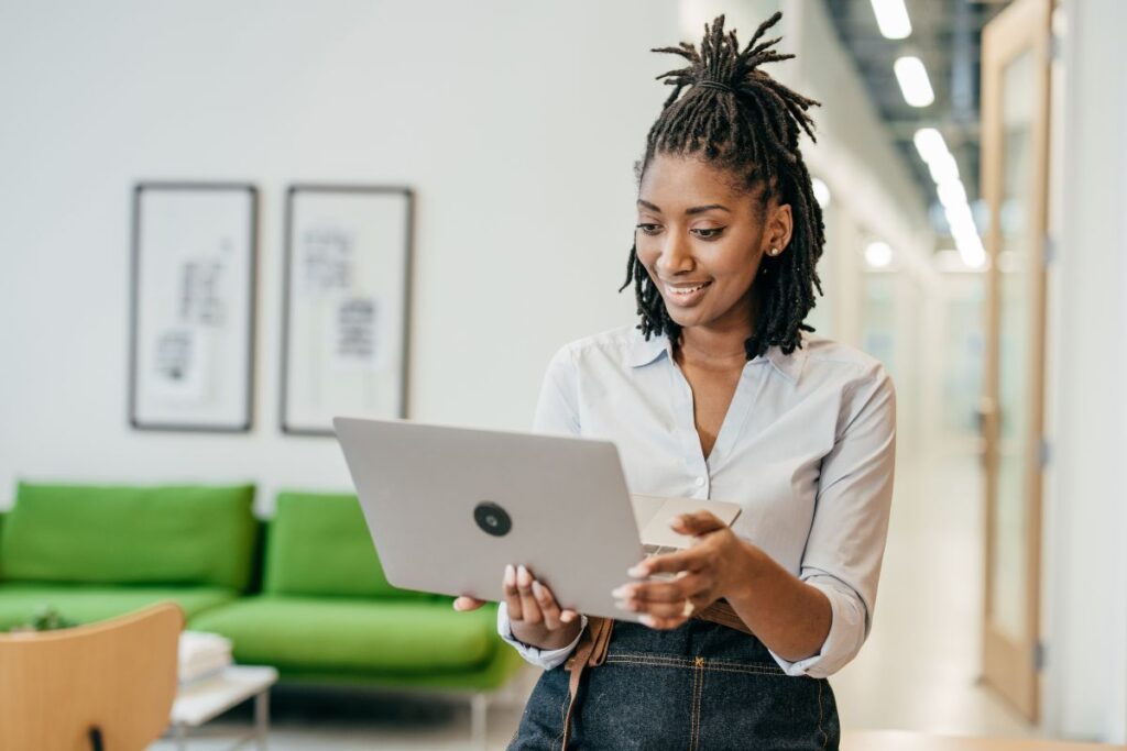 Mulher sorridente pesquisa opções de seguro em um laptop, demonstrando a facilidade de planejamento com seguro.