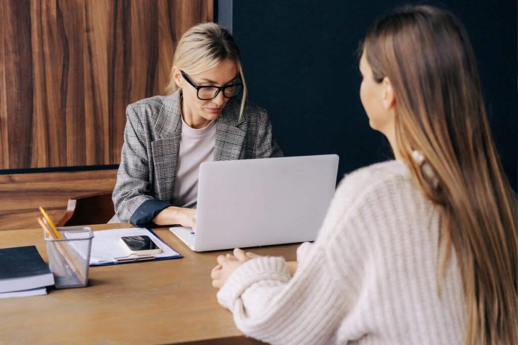 Corretora de seguros explicando termos da apólice para cliente durante consultoria sobre contrato de seguro