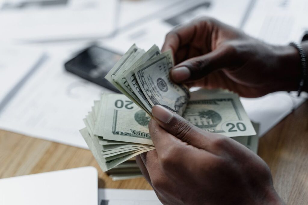 Pessoa contando notas de dinheiro em mesa de trabalho organizando reserva de emergência e controlando finanças pessoais