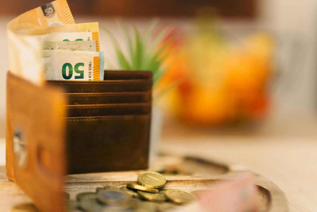 Carteira marrom com notas de euro e moedas espalhadas representando organização acessível