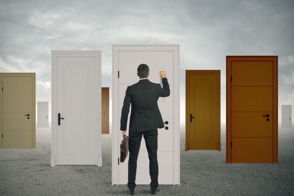 Empresário batendo em uma das muitas portas, simbolizando a escolha e a busca por novas oportunidades de negócio e crescimento.