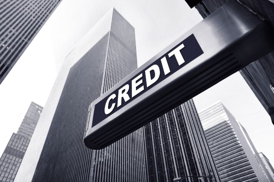 Placa de crédito em distrito financeiro cercado por prédios comerciais representando acesso a linhas de crédito e serviços bancários