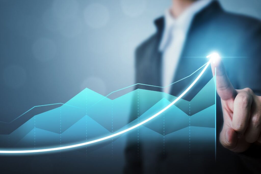 Mão de um executivo apontando para uma linha de crescimento ascendente em um gráfico azul, simbolizando estratégias de sucesso.