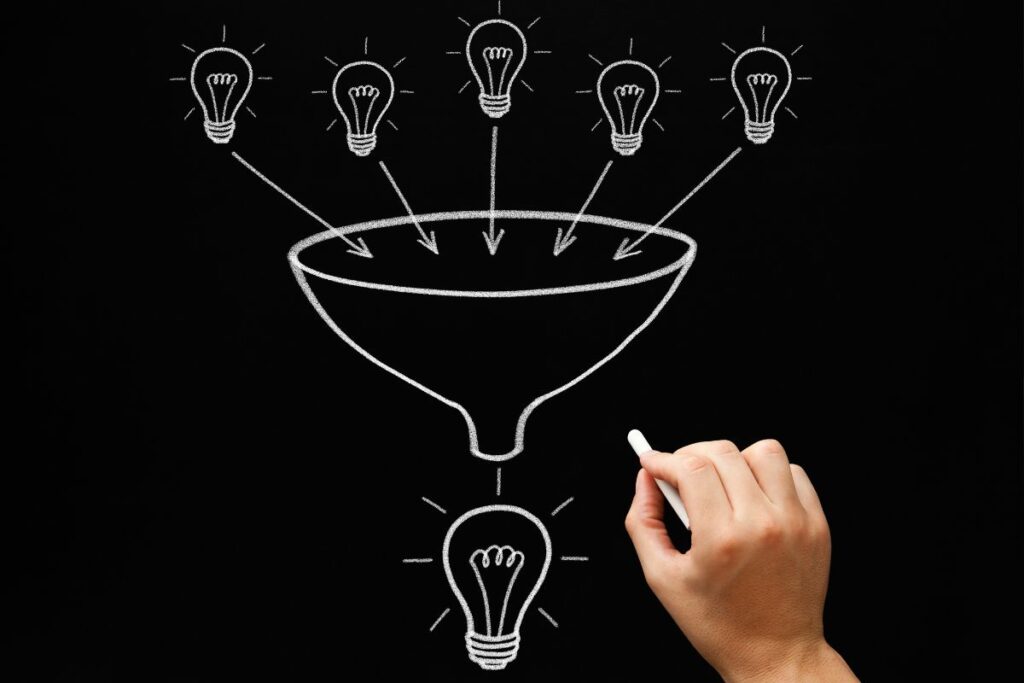 Desenho de um funil em um quadro negro, transformando múltiplas ideias em uma única solução, indicando estratégias de inovação.